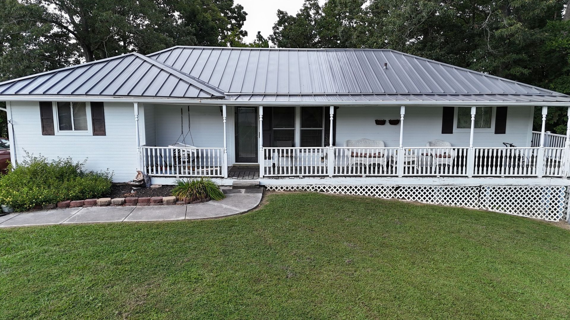 A white house with a metal roof and a large porch.