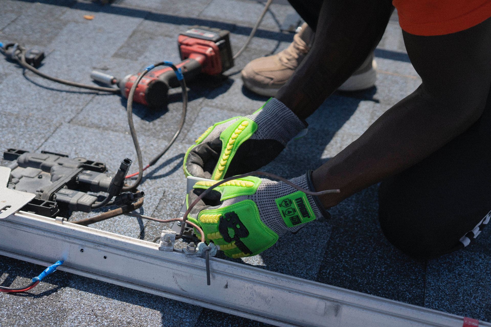 Person installing solar panels on a rooftop with green gloves and power tools