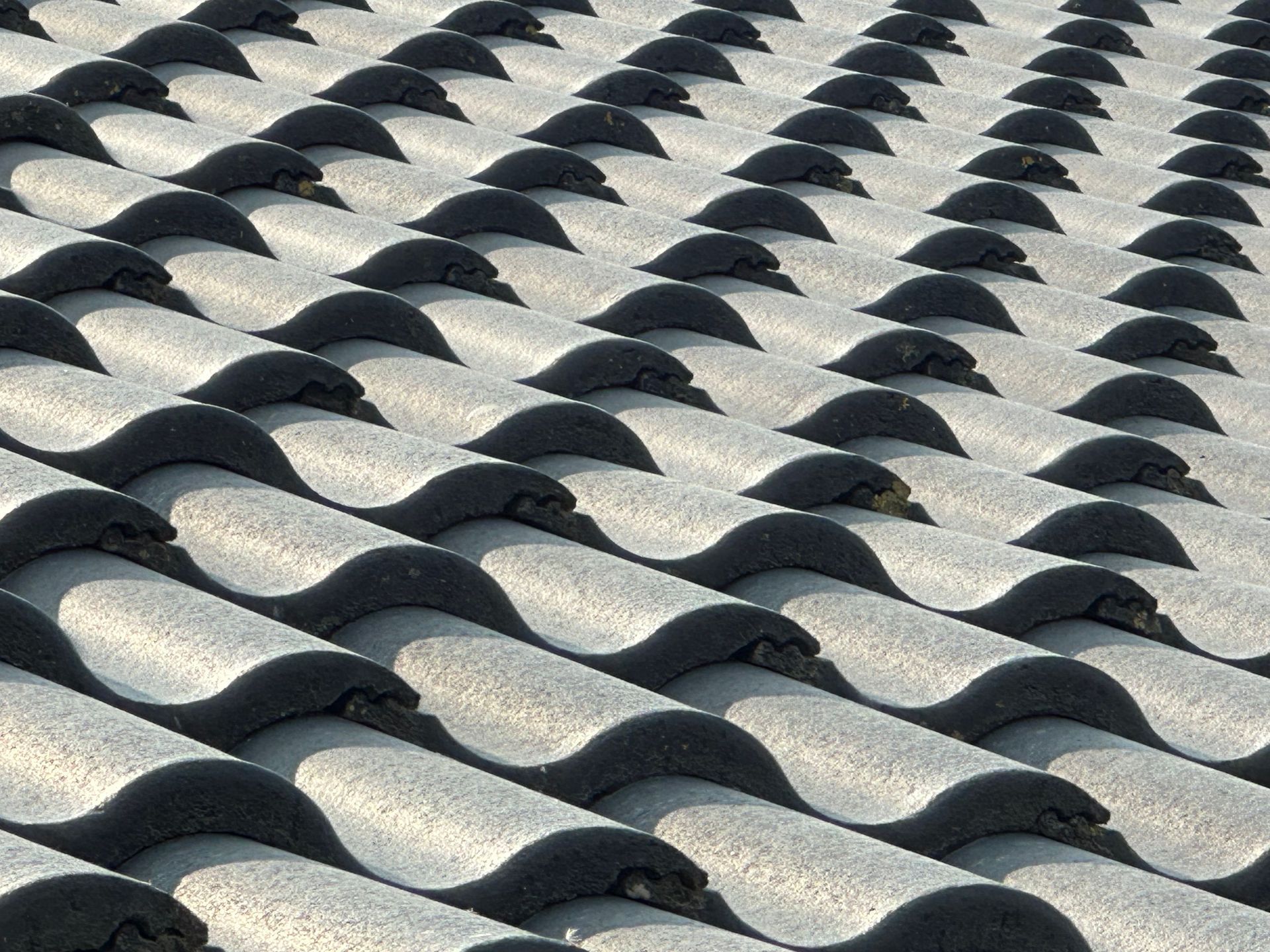 Wavy gray roof tiles in a repeating pattern, lit by sunlight
