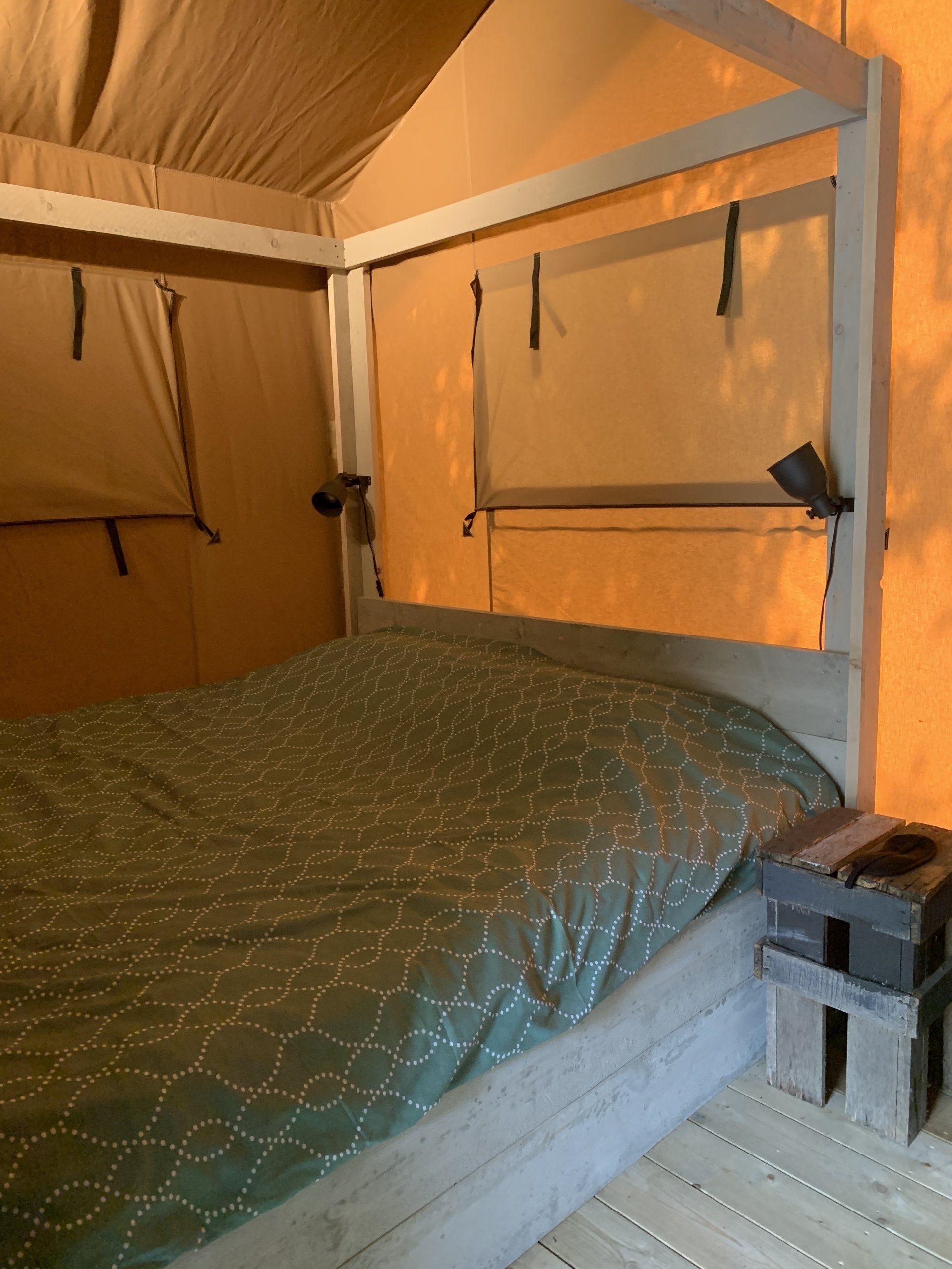 Een bed in een tent met een groene deken