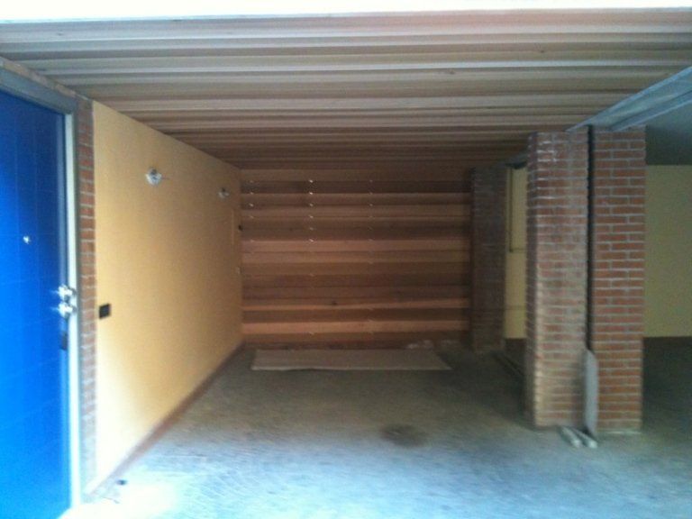 Un garage vuoto con una porta blu e pilastri in mattoni