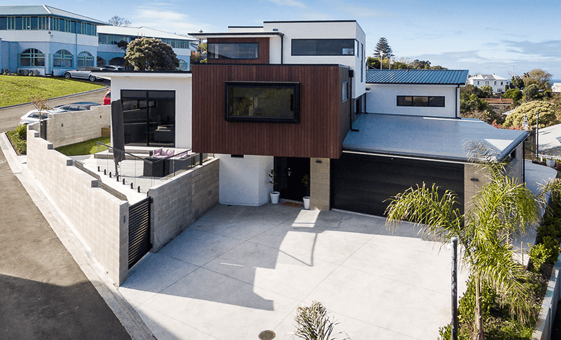 Modern two-story house with a brown wood facade, black garage, and concrete driveway.