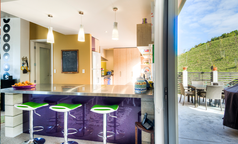 Kitchen with purple bar stools, outdoor patio, and a view of a hill.
