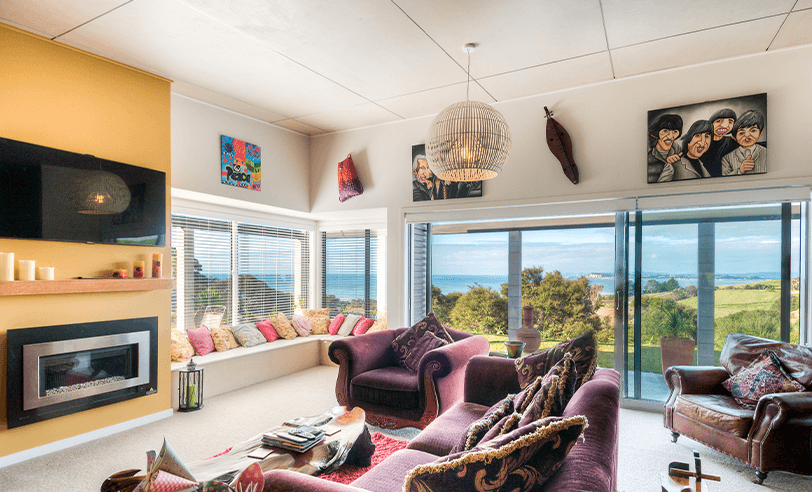 Living room with purple sofas, fireplace, and large windows overlooking a scenic view.
