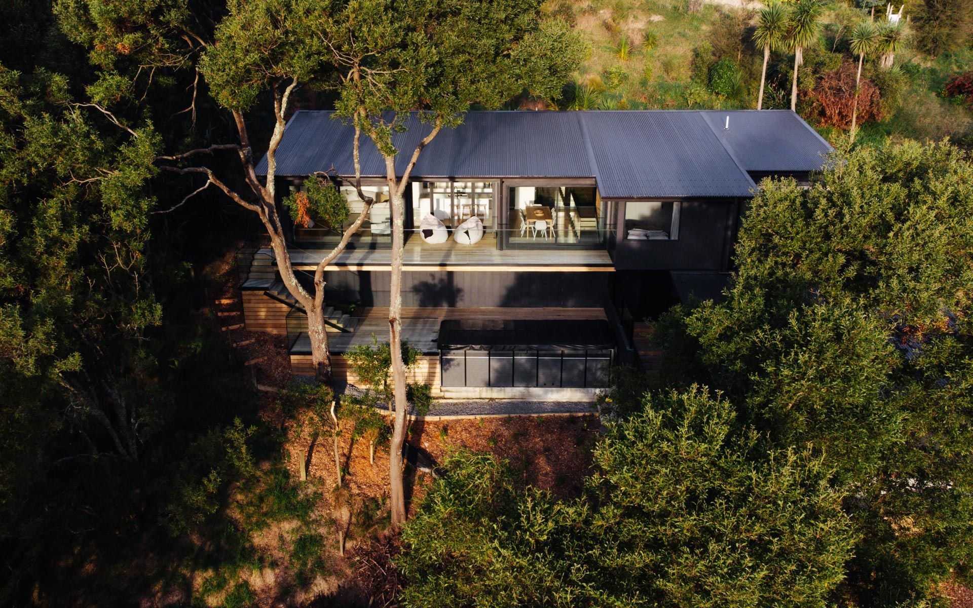 Modern black house nestled amongst green trees.