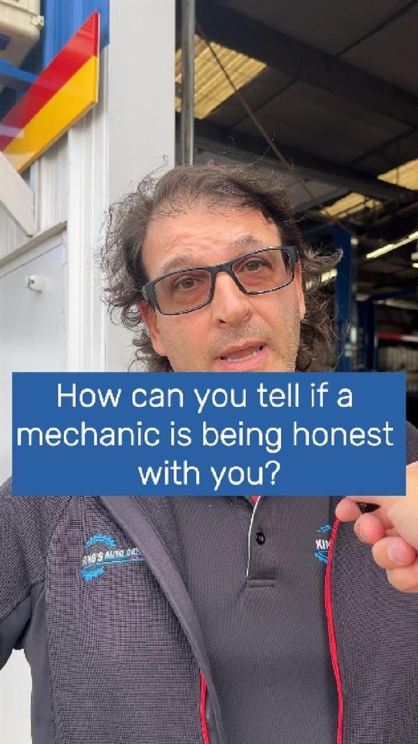 Mechanic speaking, questioning honesty. Wearing glasses, standing in a garage with text overlay: 