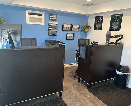 Two dark brown reception desks in an office. Light blue wall with paperwork, and decor. | King's Auto Center