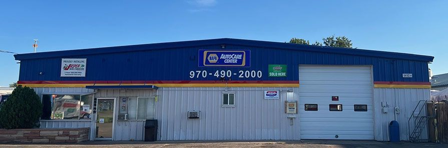 A blue auto repair shop with white metal siding and a large garage door, featuring a phone number and shop name on the exterior. | King's Auto Center