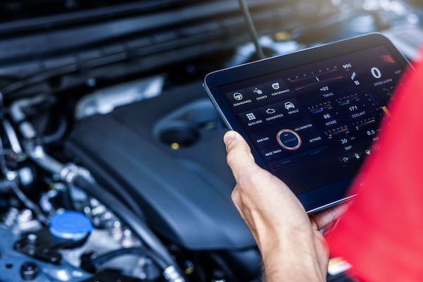 Person holding a tablet, diagnosing a car engine with diagnostic software. | King's Auto Center