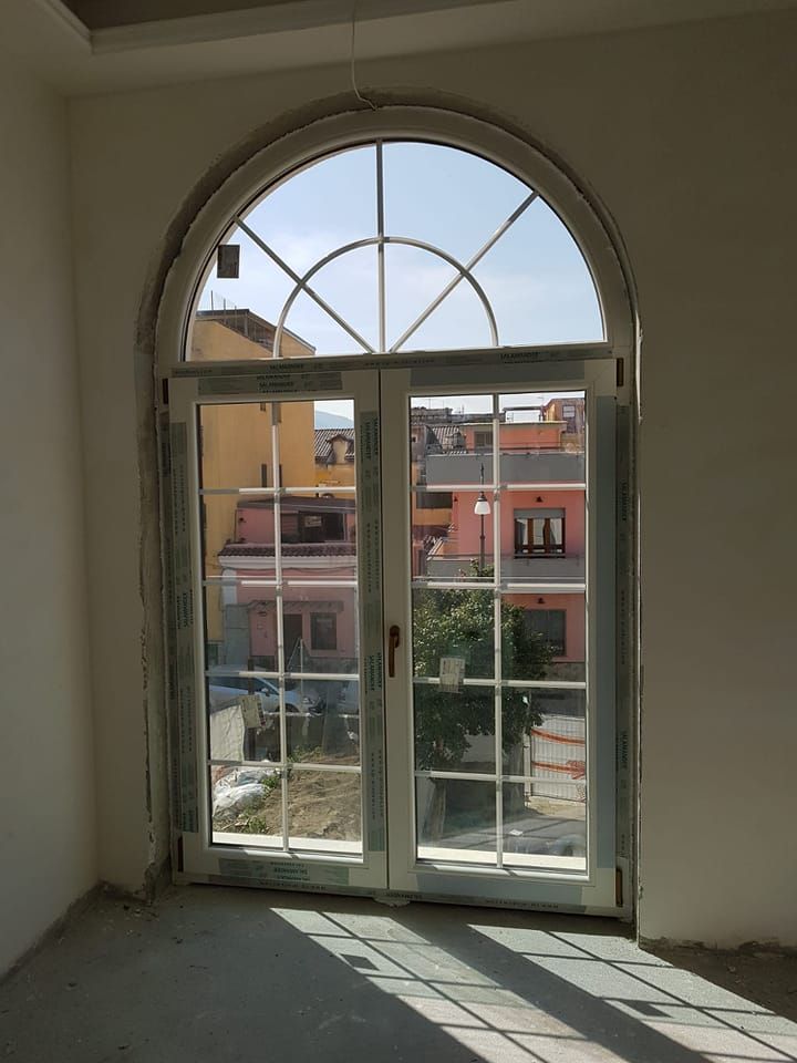 Finestra ad arco con vetri divisi, con vista su un quartiere residenziale.