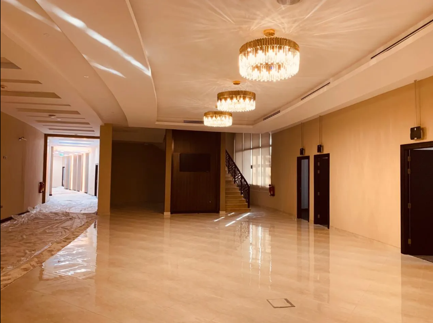 An empty hallway with a staircase and a few chandeliers