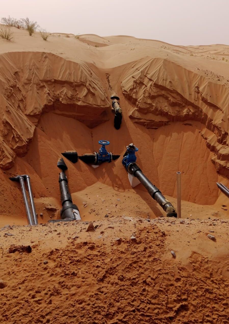 A hole in the sand with pipes coming out of it