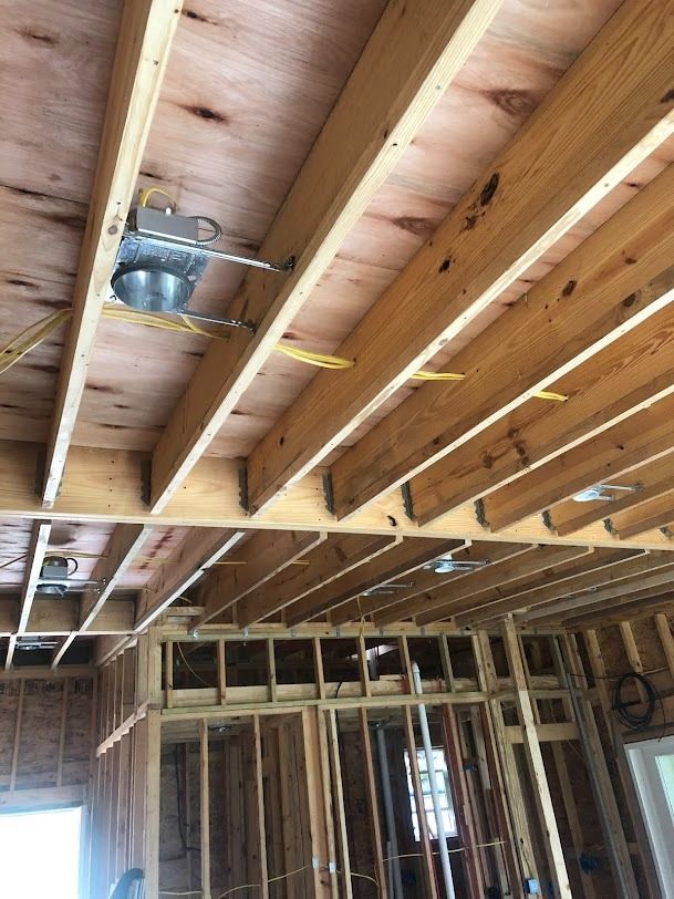Exposed ceiling joists and ductwork in a framed room under construction.