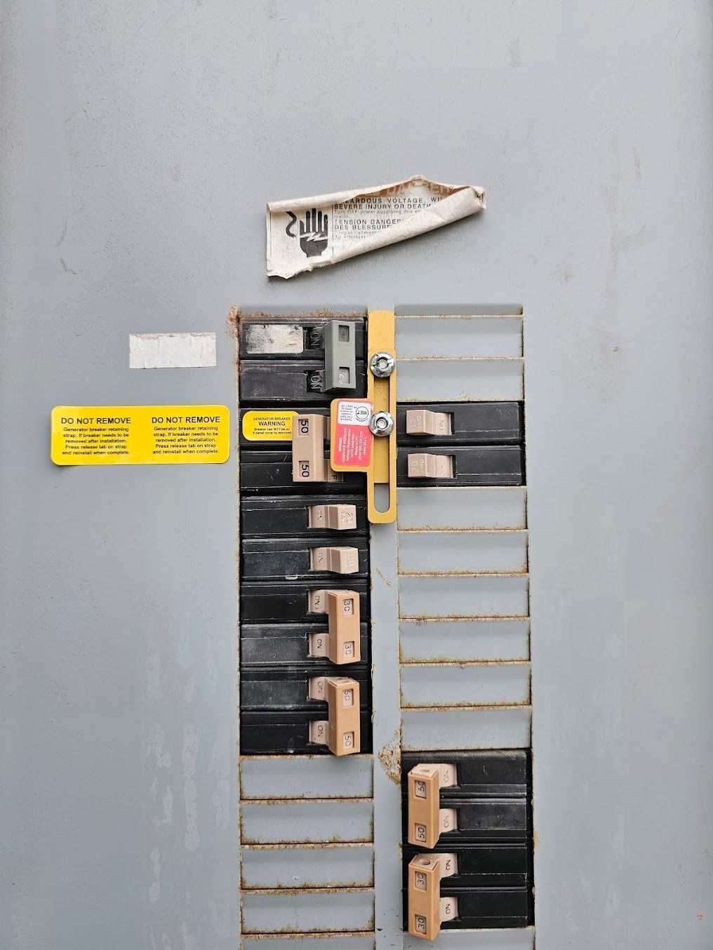 Open electrical breaker panel with labeled switches and a torn sign above it