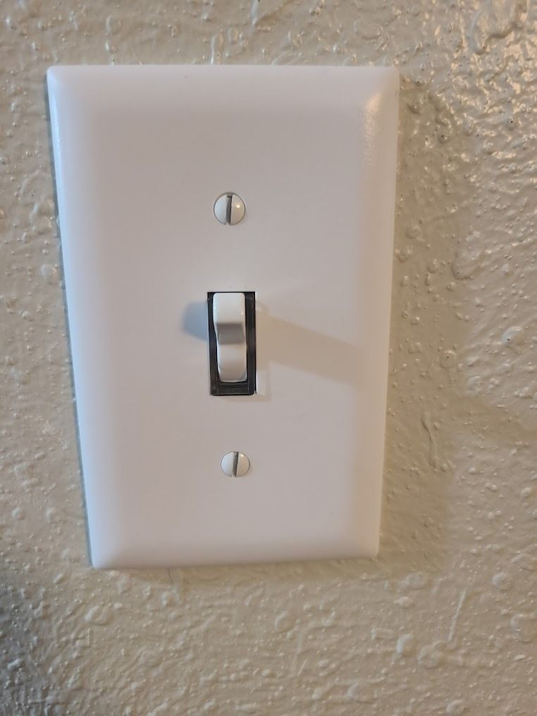 White wall light switch plate with a single black toggle switch.