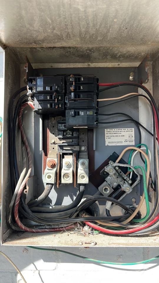 Open electrical panel with circuit breakers, wiring, and a meter inside a metal enclosure