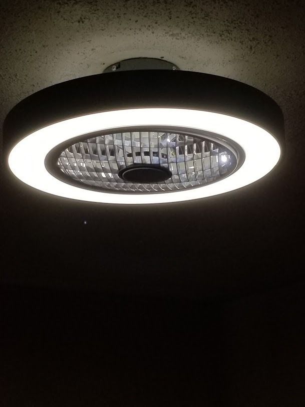Round ceiling light with a bright white ring and textured center against a dark ceiling