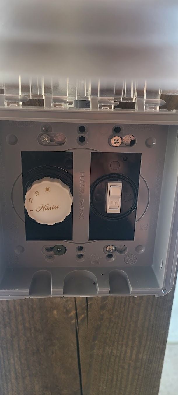 Electrical outlet panel with a round white control on the left and a black switch on the right.