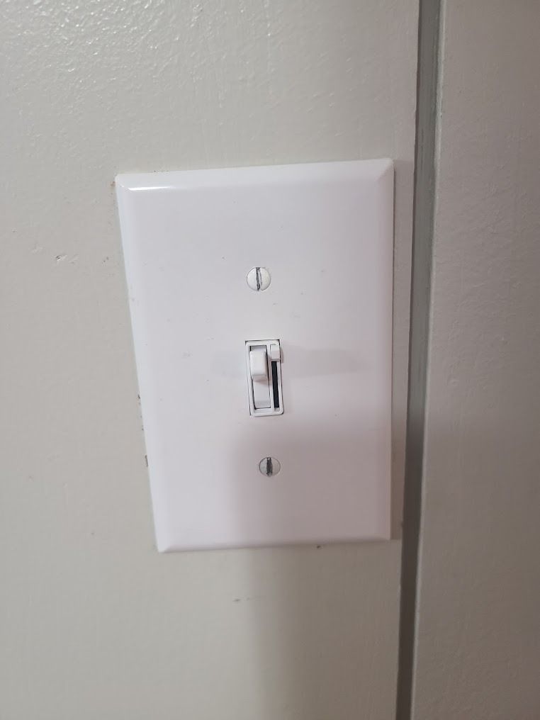 White wall light switch plate with a small toggle switch.