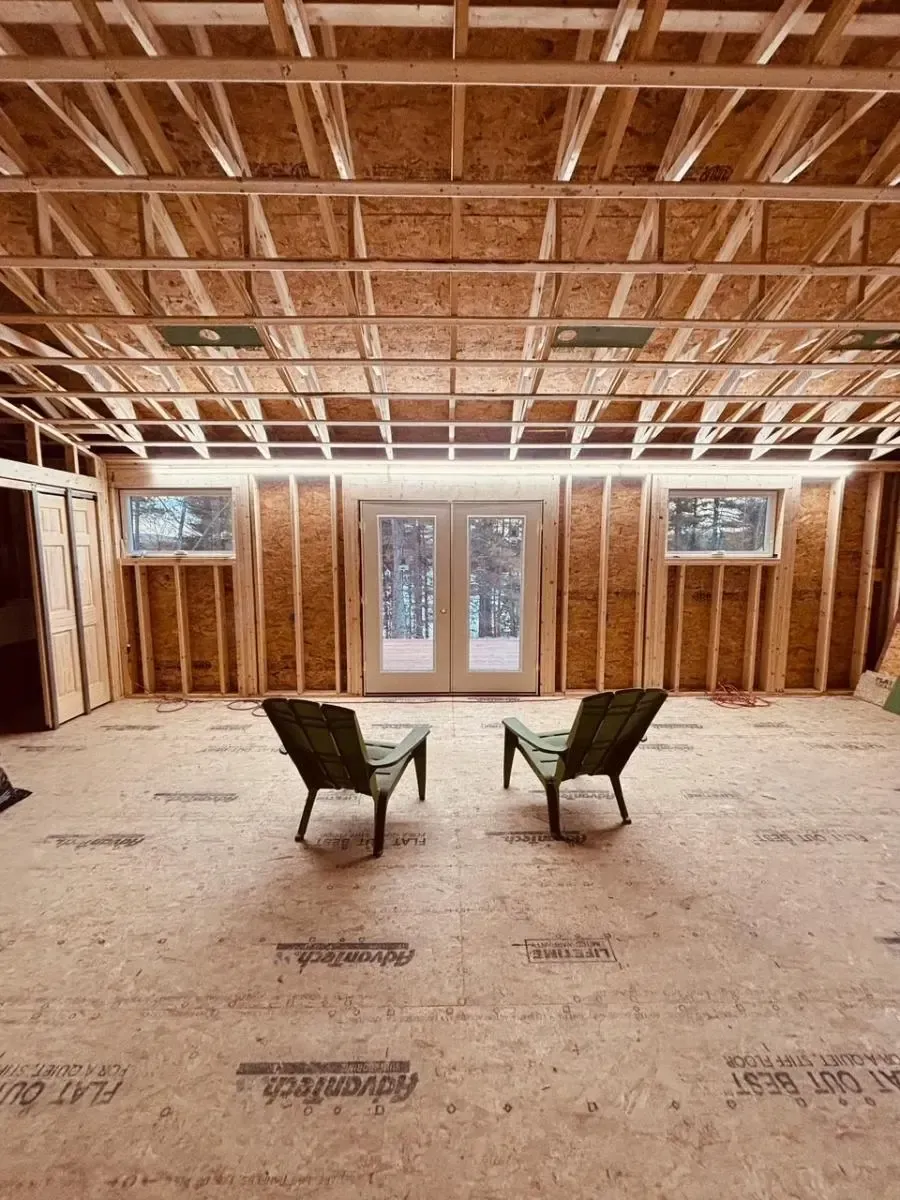 Interior framing of a room with two chairs, windows, and double doors. Construction in progress.