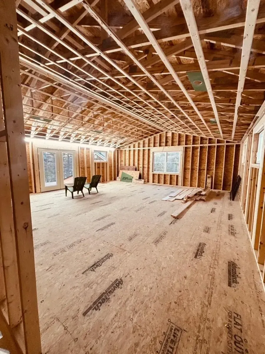Interior of a new home under construction. Wood framing of walls, floor, and ceiling visible.