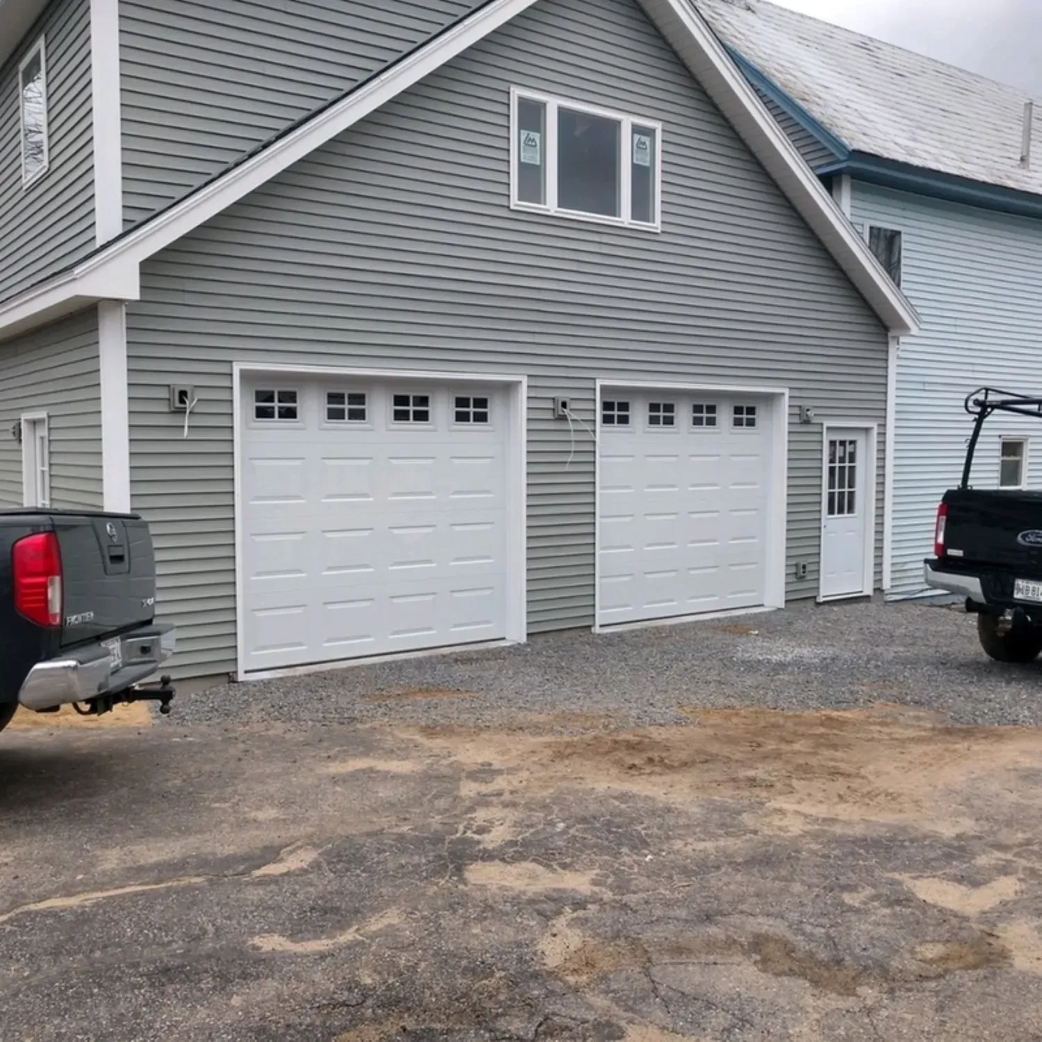 A truck is parked in front of a garage with three garage doors.