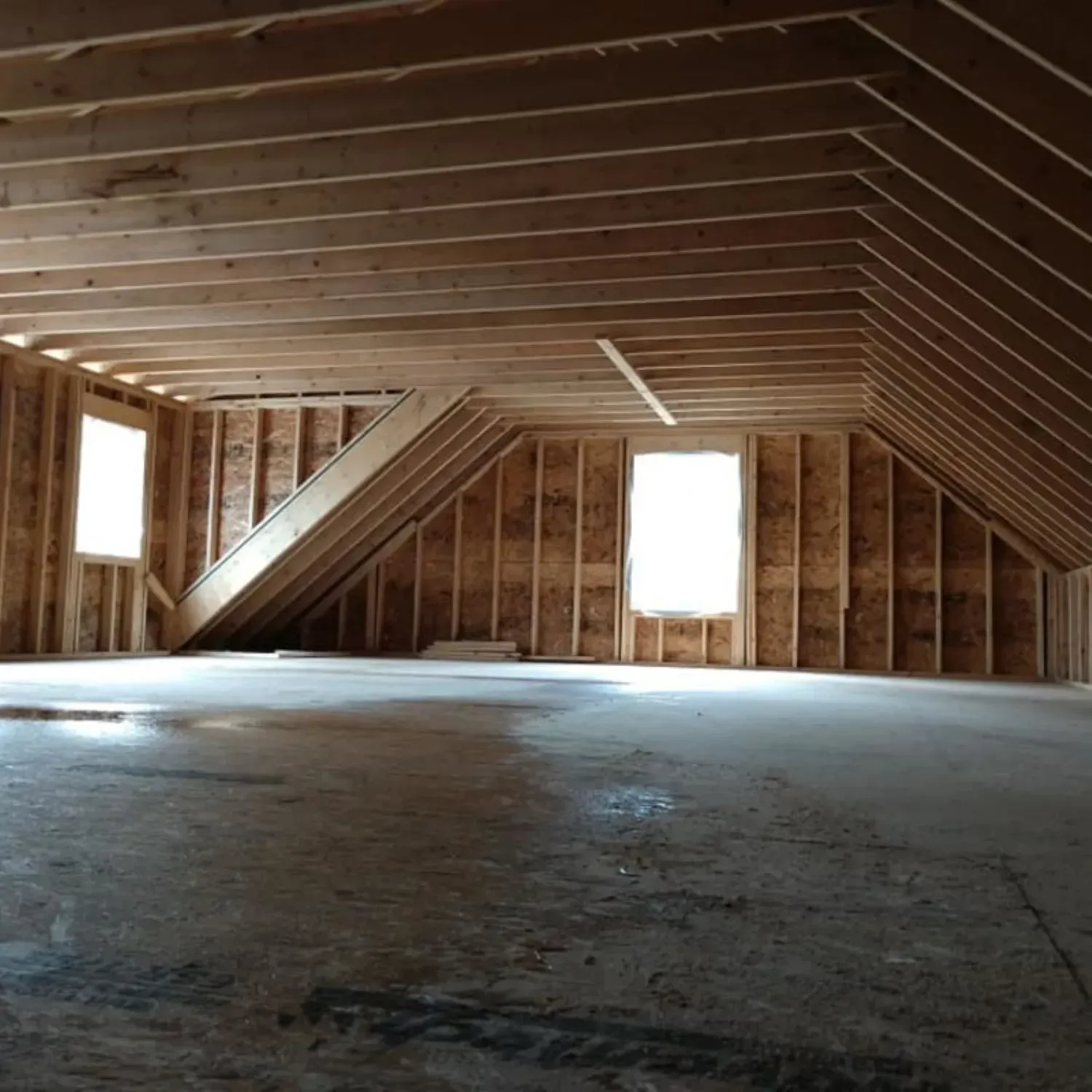 An empty attic with a vaulted ceiling and a few windows