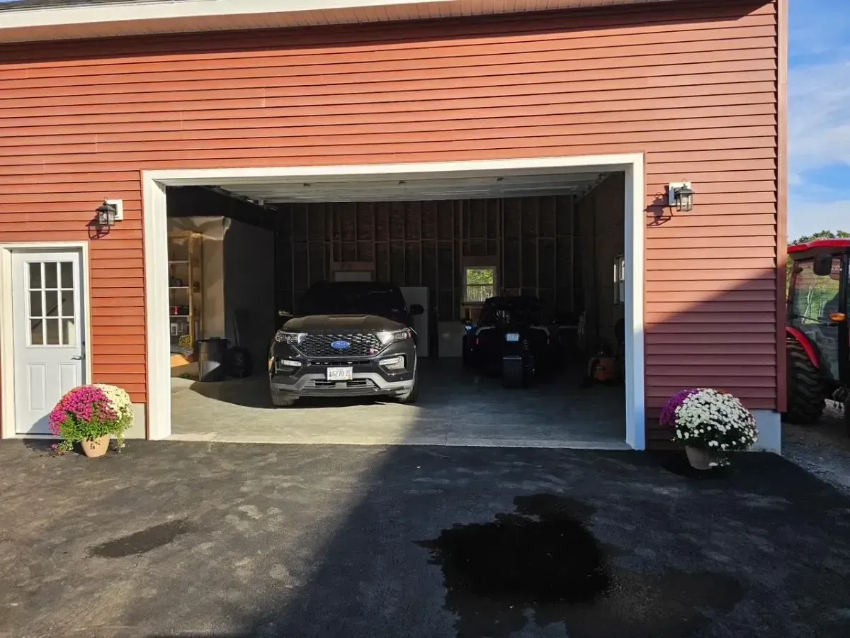 Red garage with open door, black SUV and motorcycle inside, small white door left.