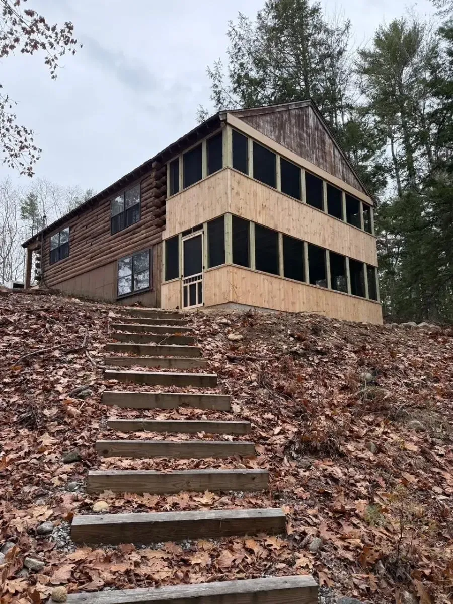 Wooden cabin with exterior stairs and multi-level screened porch.