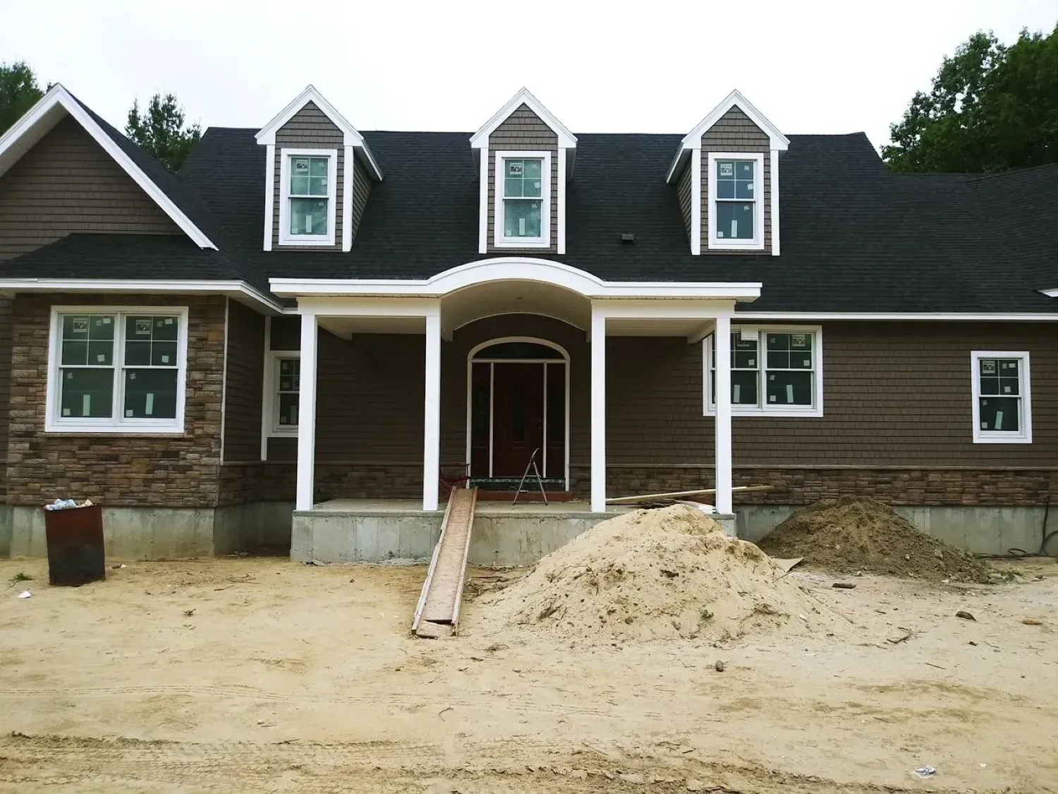 A house under construction with a large pile of dirt in front of it