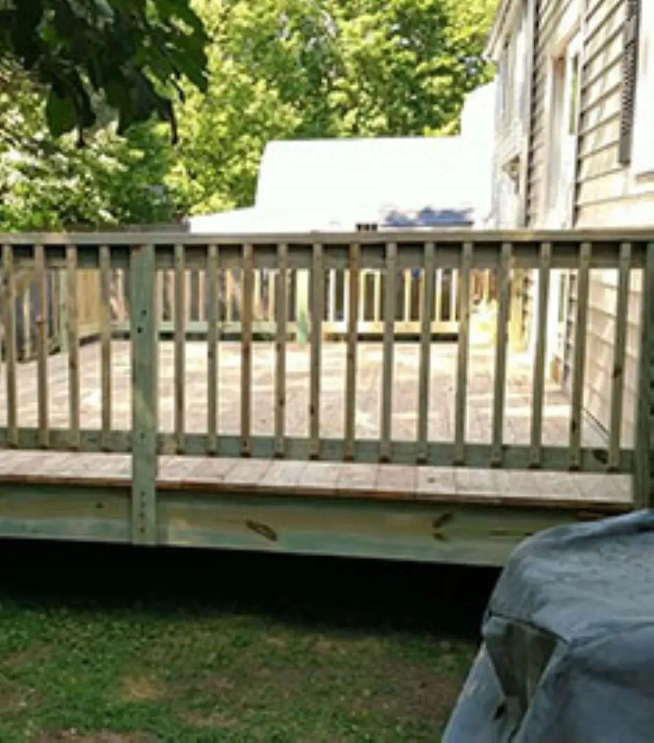 A wooden deck with a railing leading to a house.