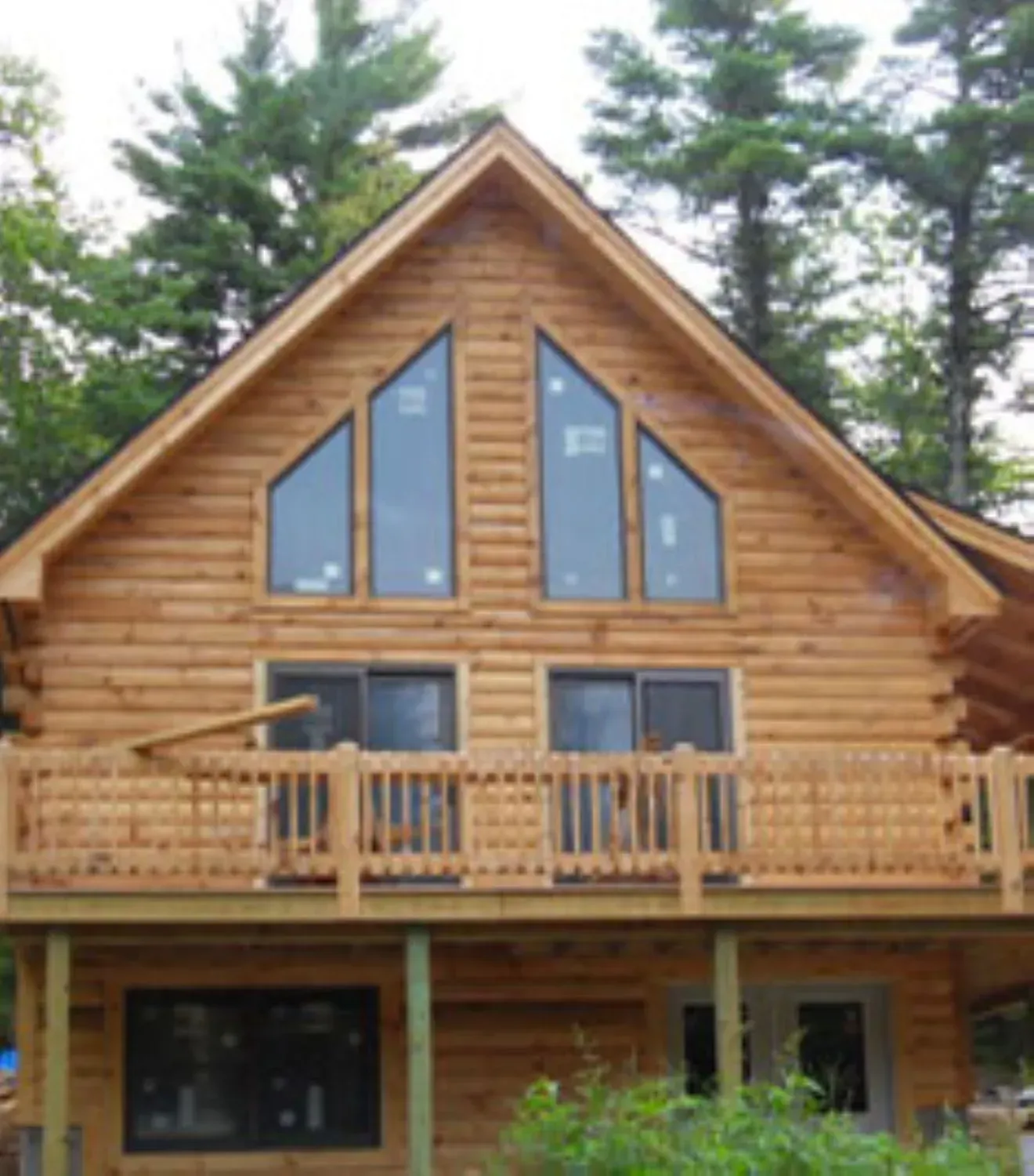 A large log cabin with a balcony and large windows