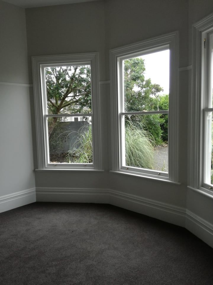 An empty room with a lot of windows and a tree in the background.