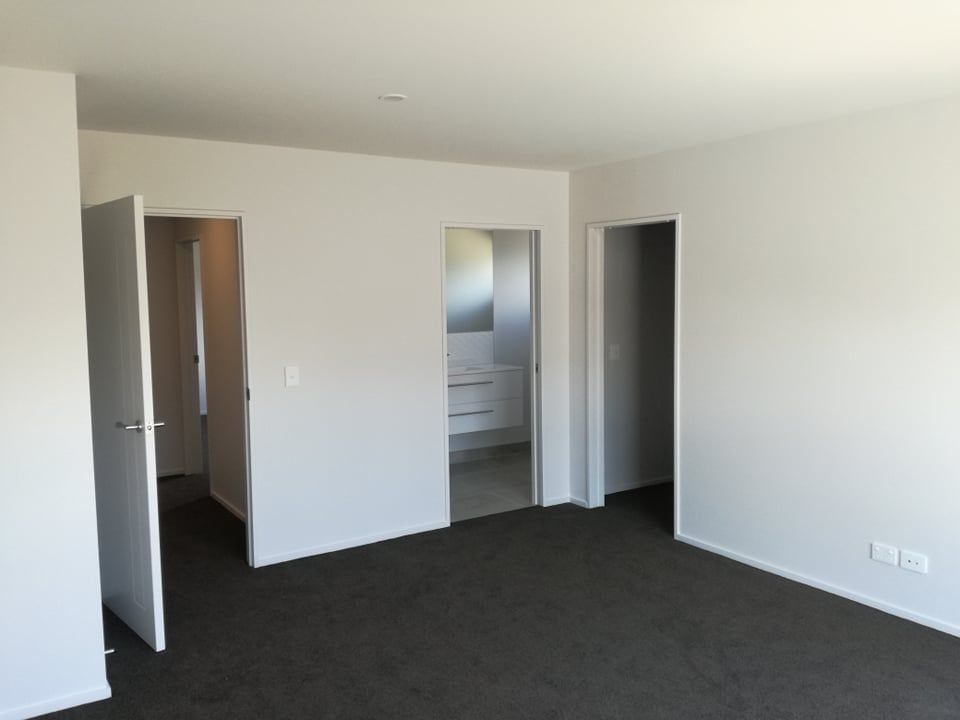 An empty room with a black carpet and white walls