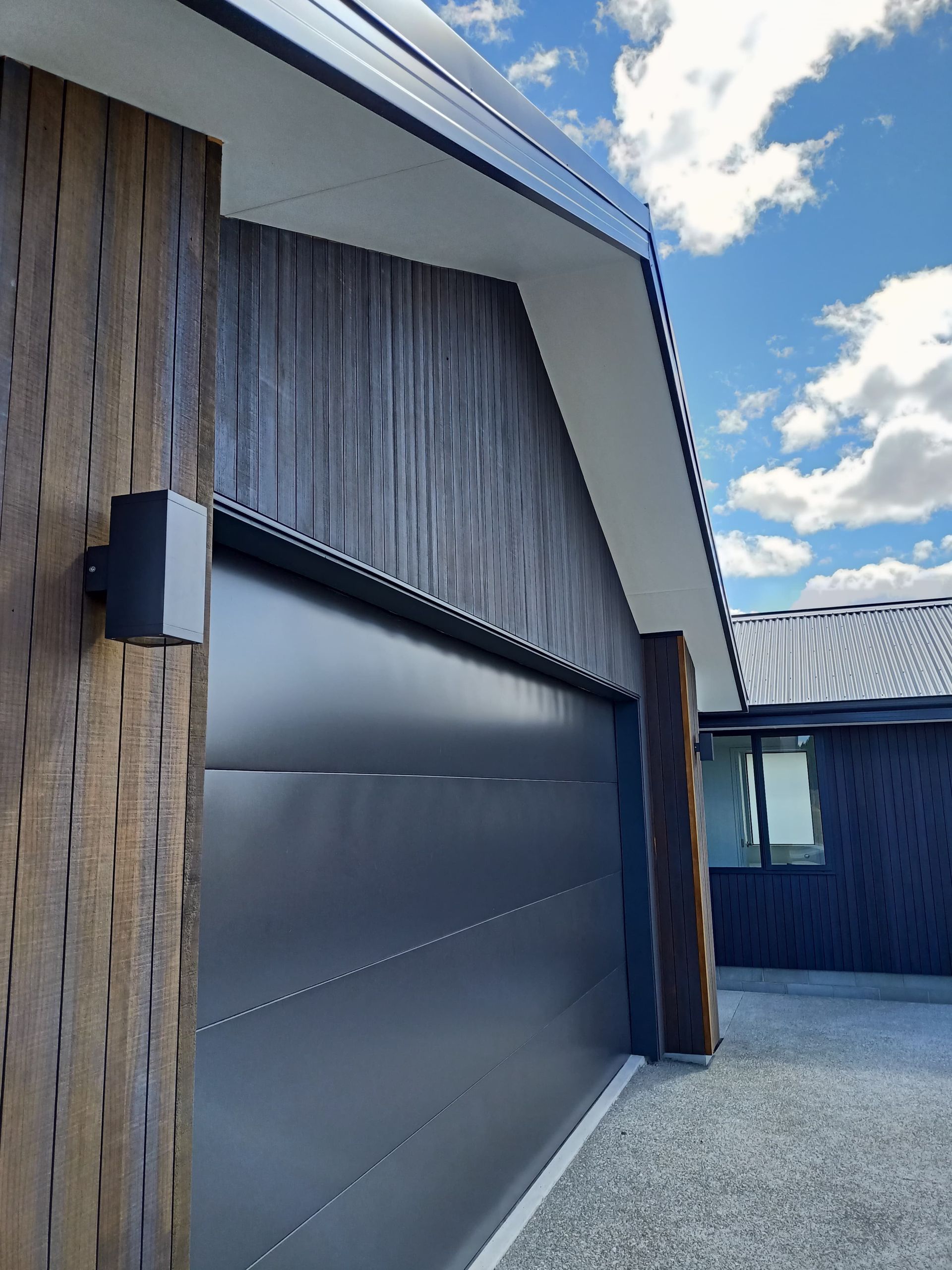 A black garage door is on the side of a house.