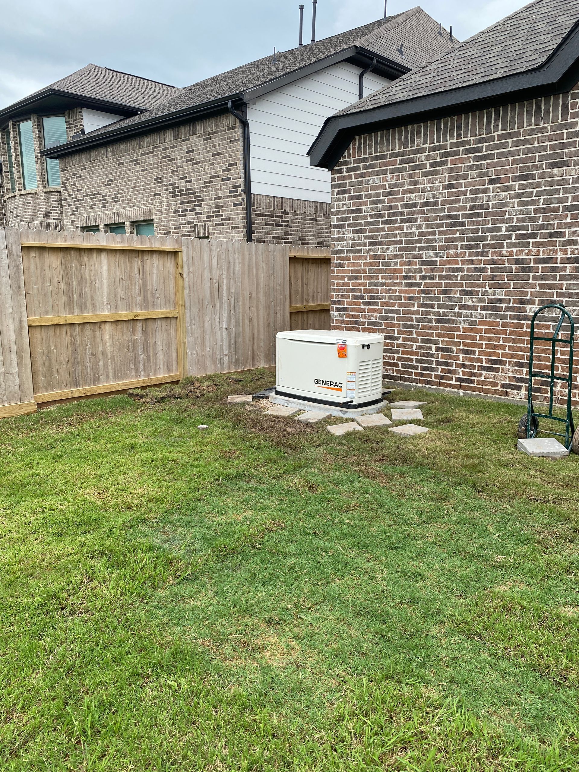 There is a generator in the backyard of a house.