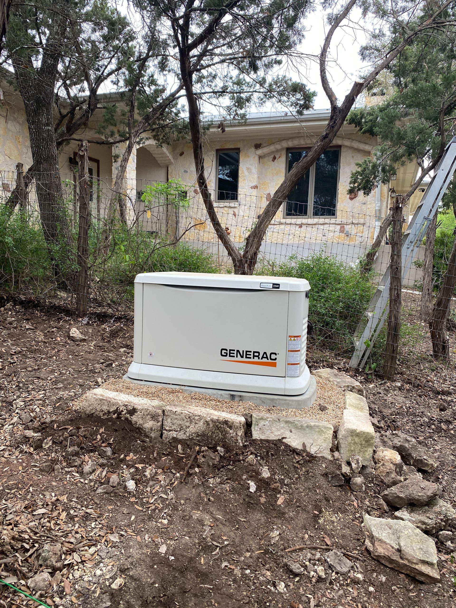 A generator is sitting on top of a rock in front of a house.