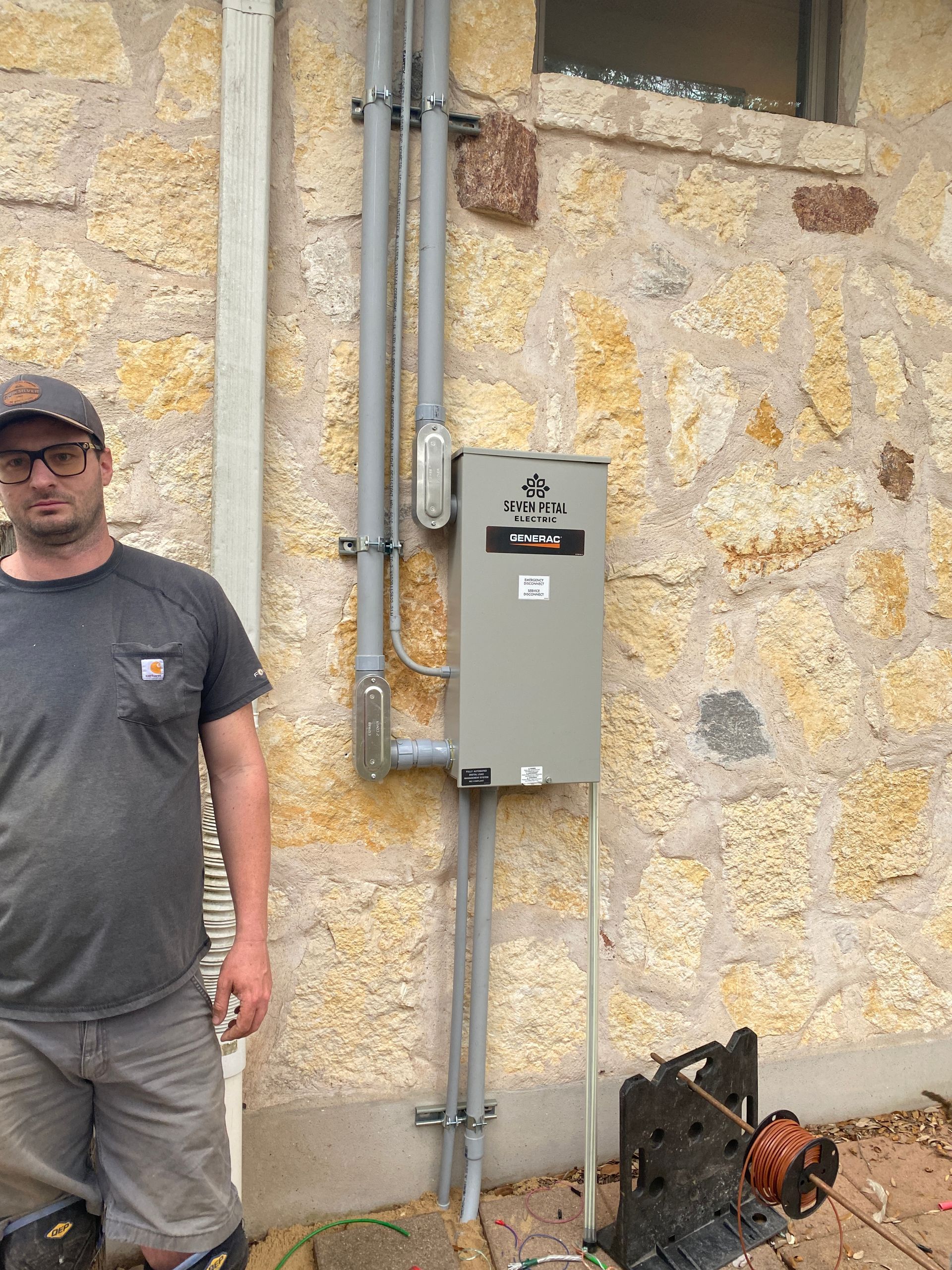 A man is standing in front of a stone wall next to a box.
