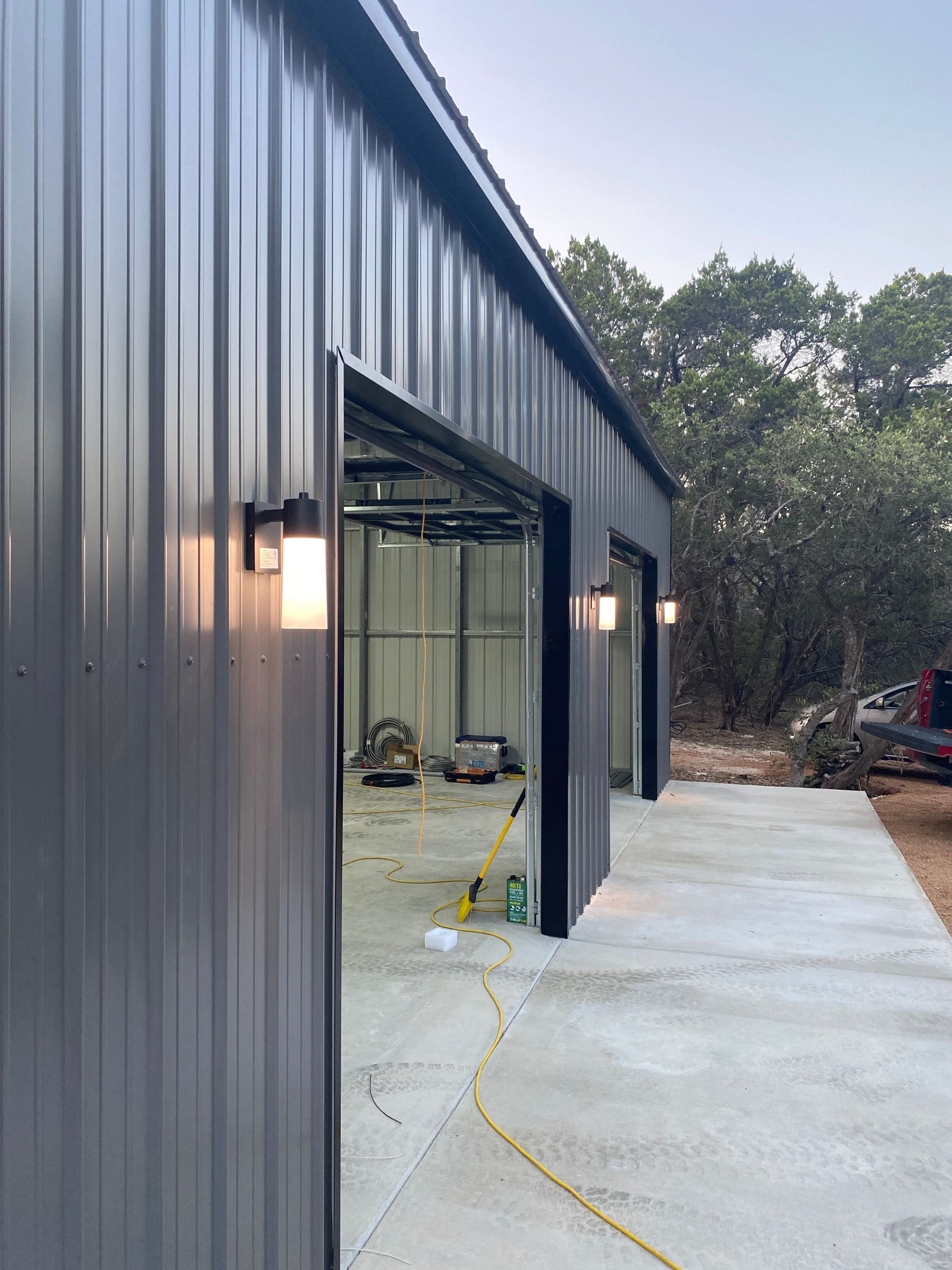 A black metal garage with a concrete driveway and two garage doors.