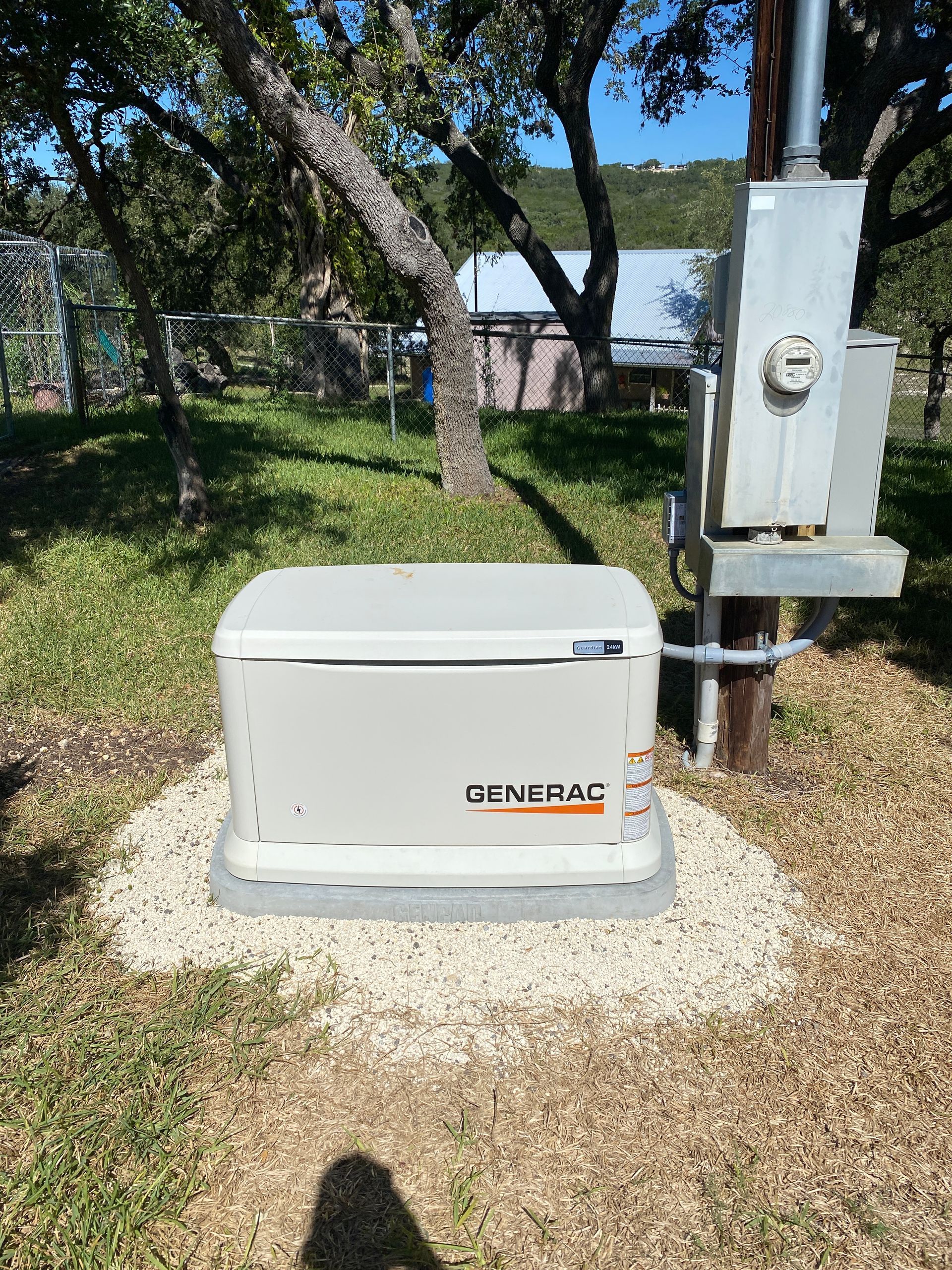 A generator is sitting in the grass next to a power pole.
