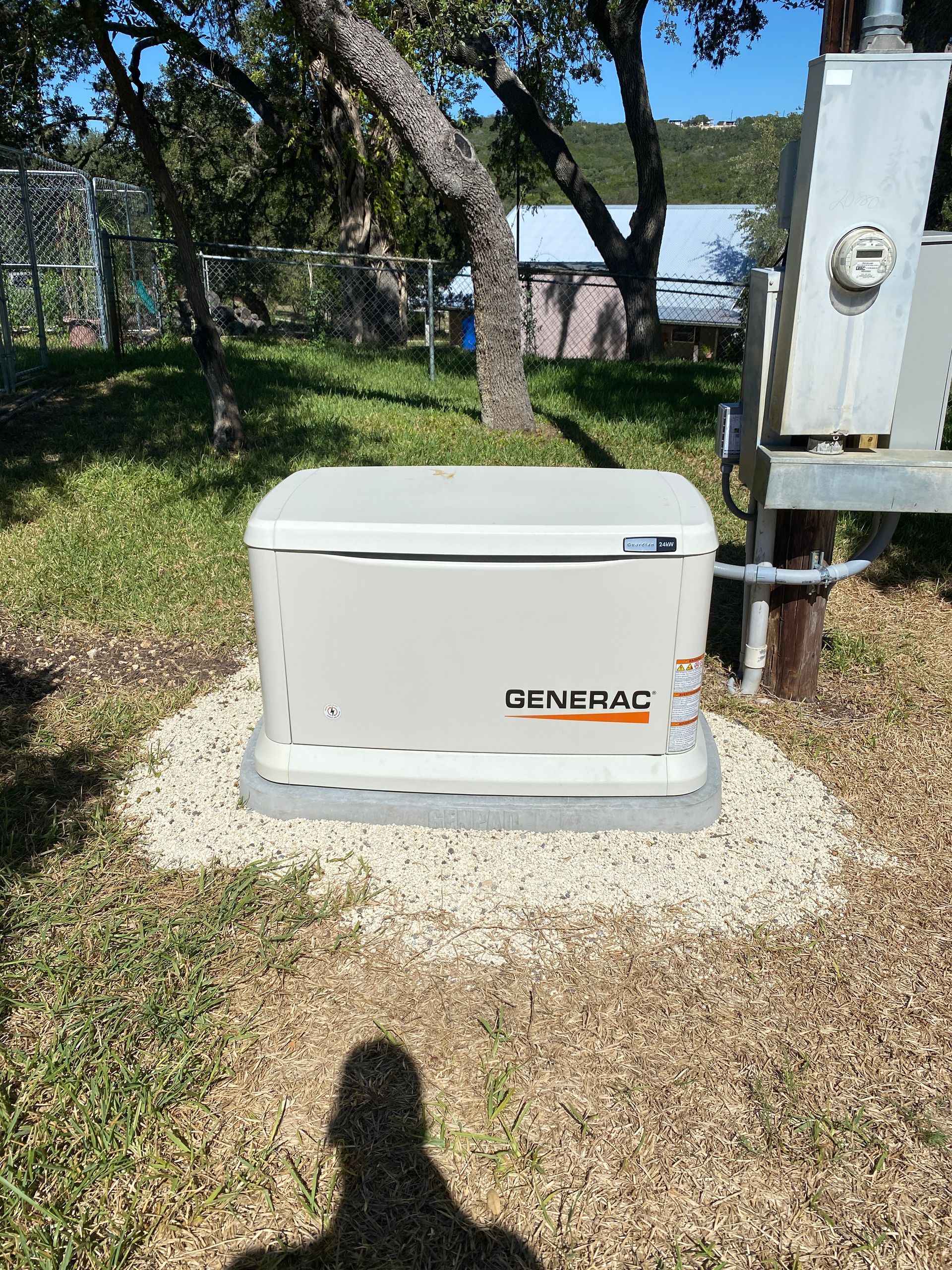 A generator is sitting in the middle of a grassy field.