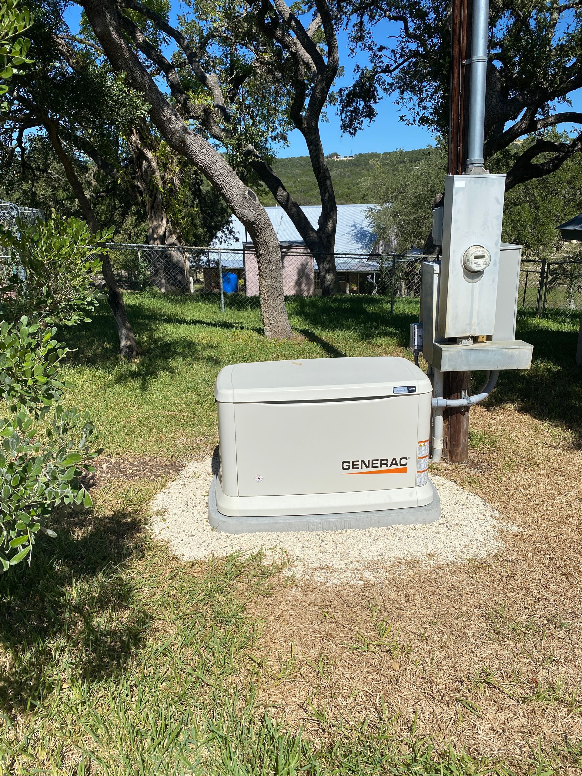 A generator is sitting in the grass next to a power pole.
