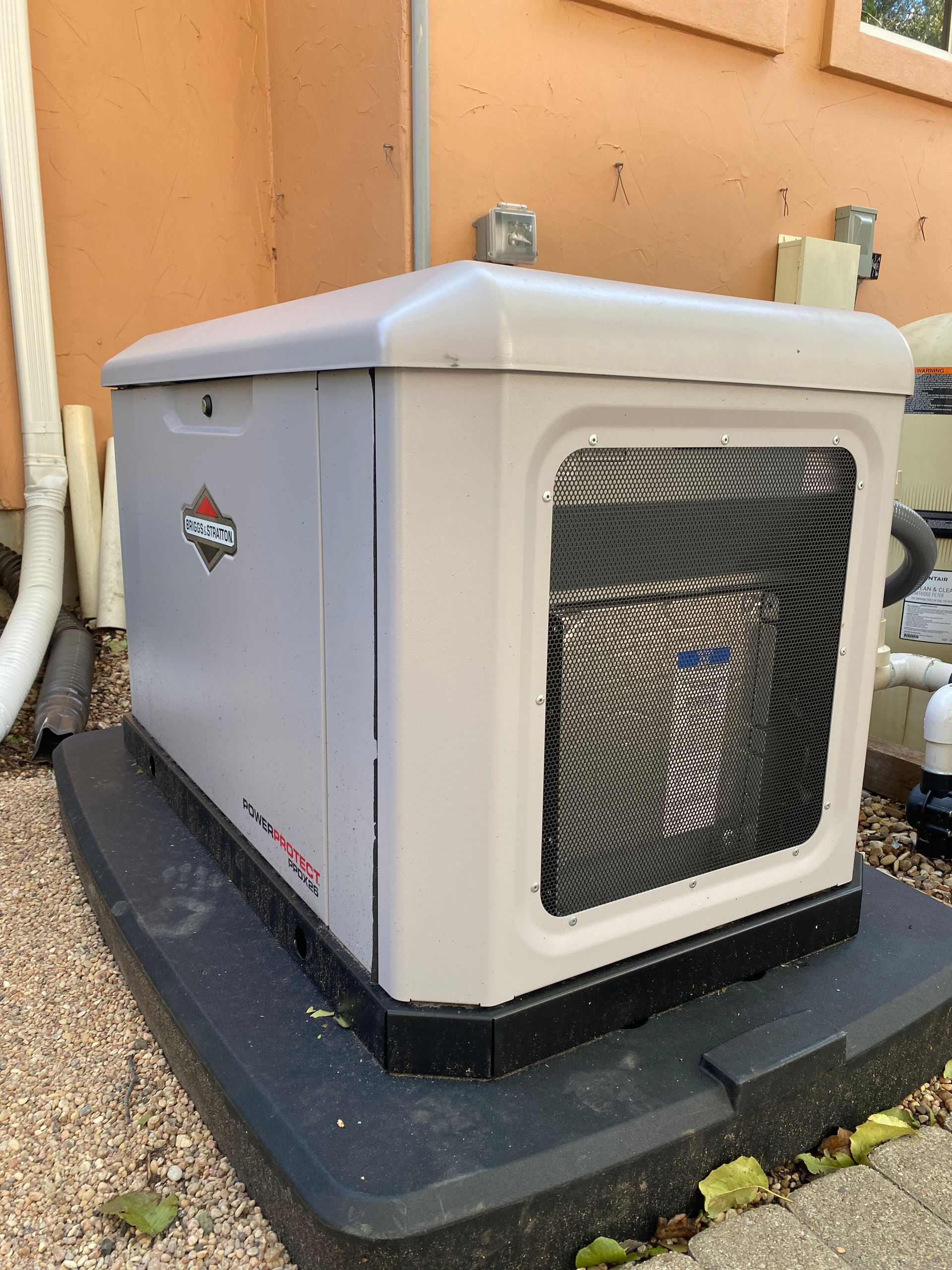 A generator is sitting on the side of a building.