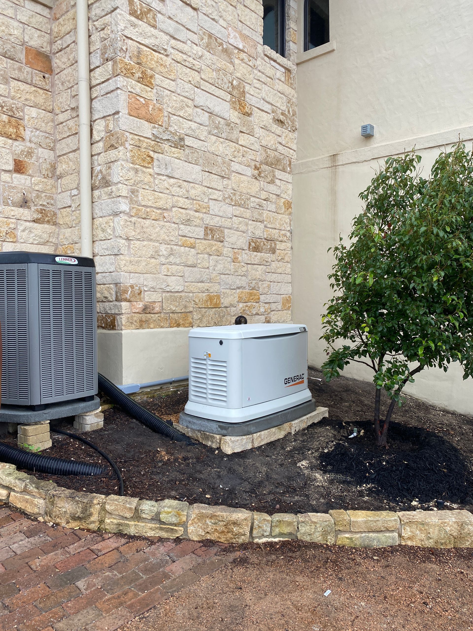 A generator is sitting on the side of a house next to a tree.