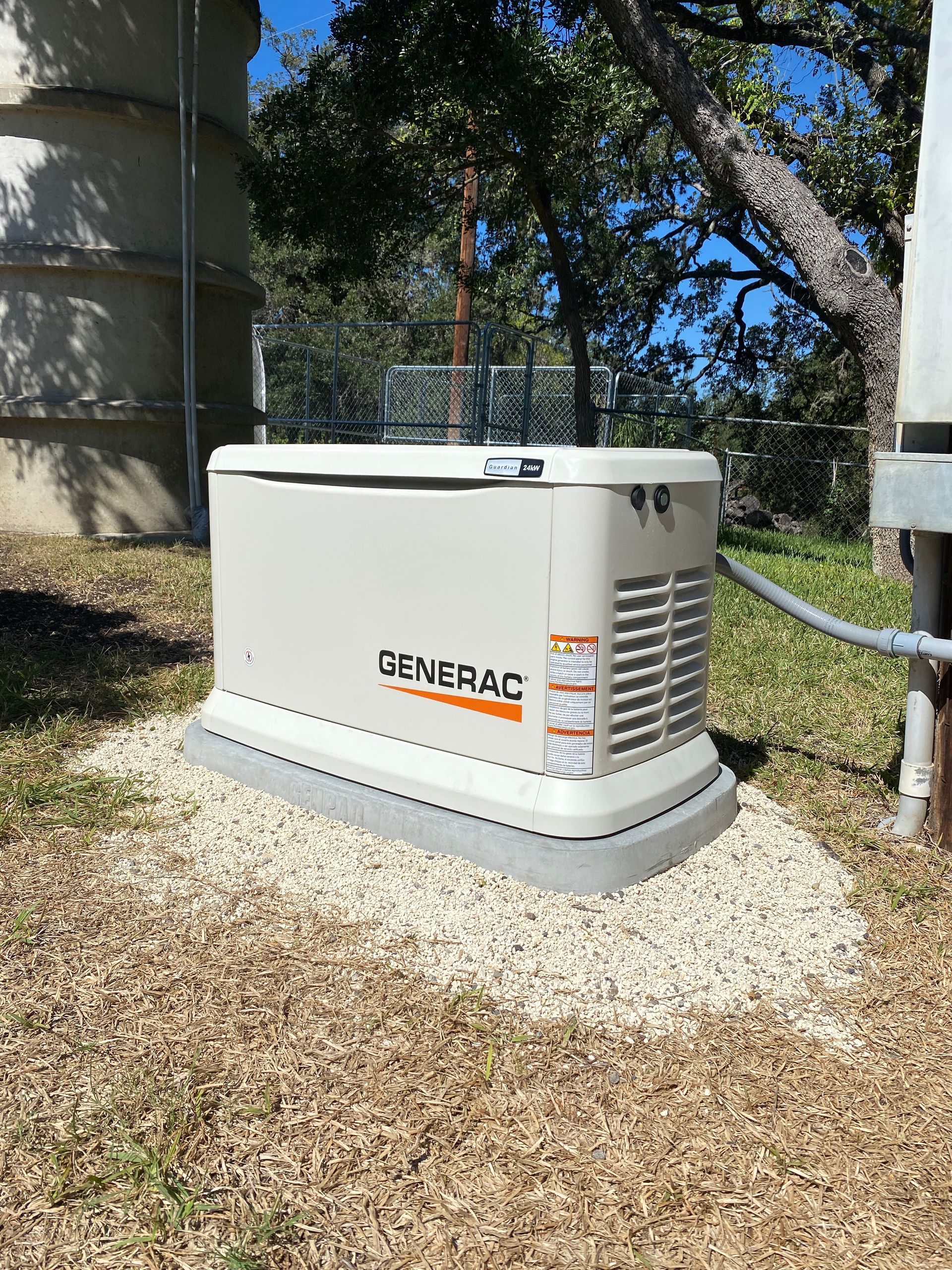 A generator is sitting in the grass next to a building.