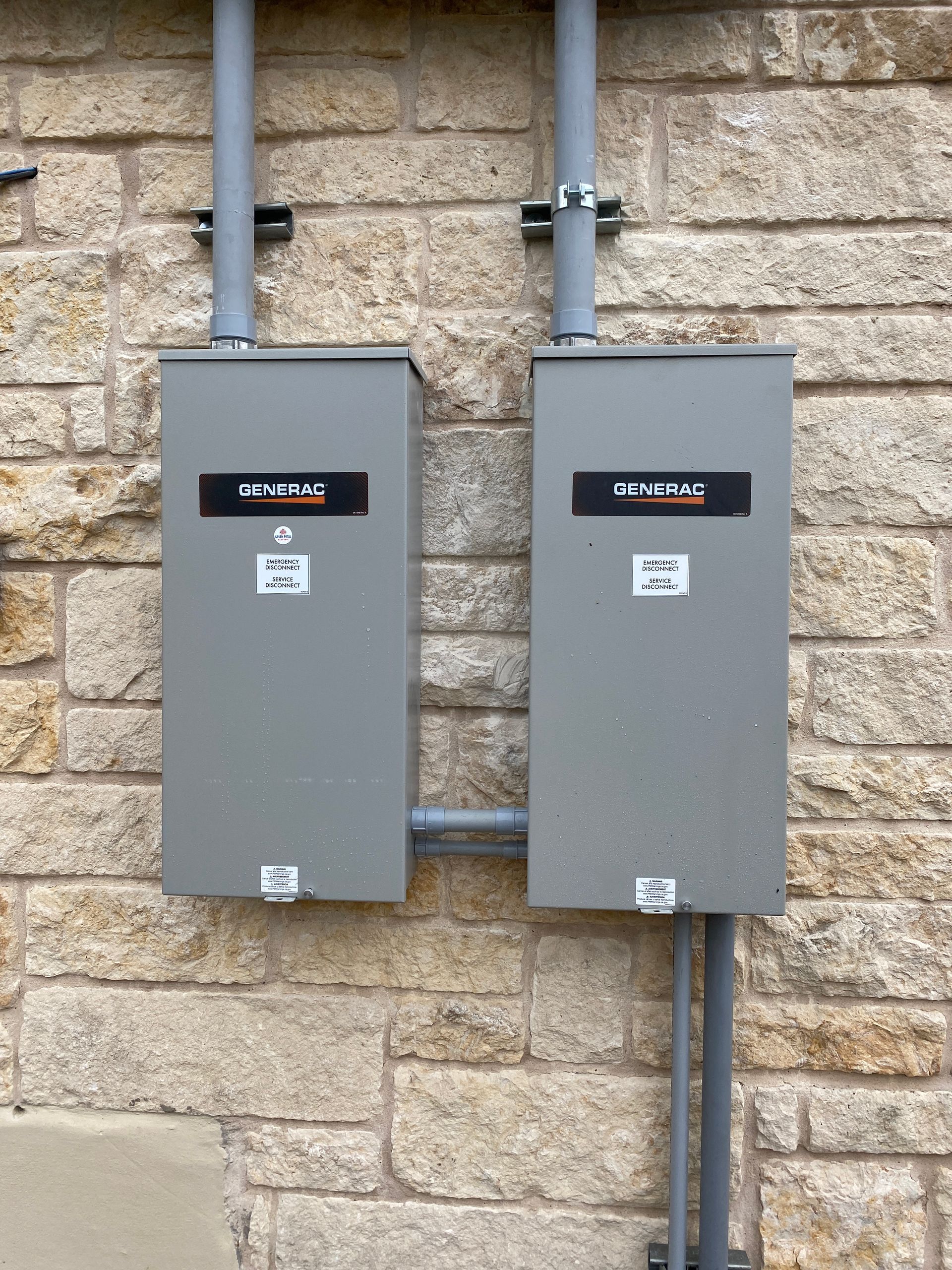 Two electrical boxes are attached to a brick wall