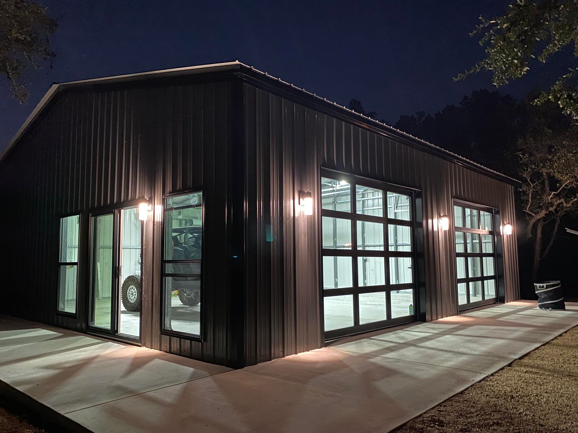 A large metal building with a lot of windows is lit up at night.