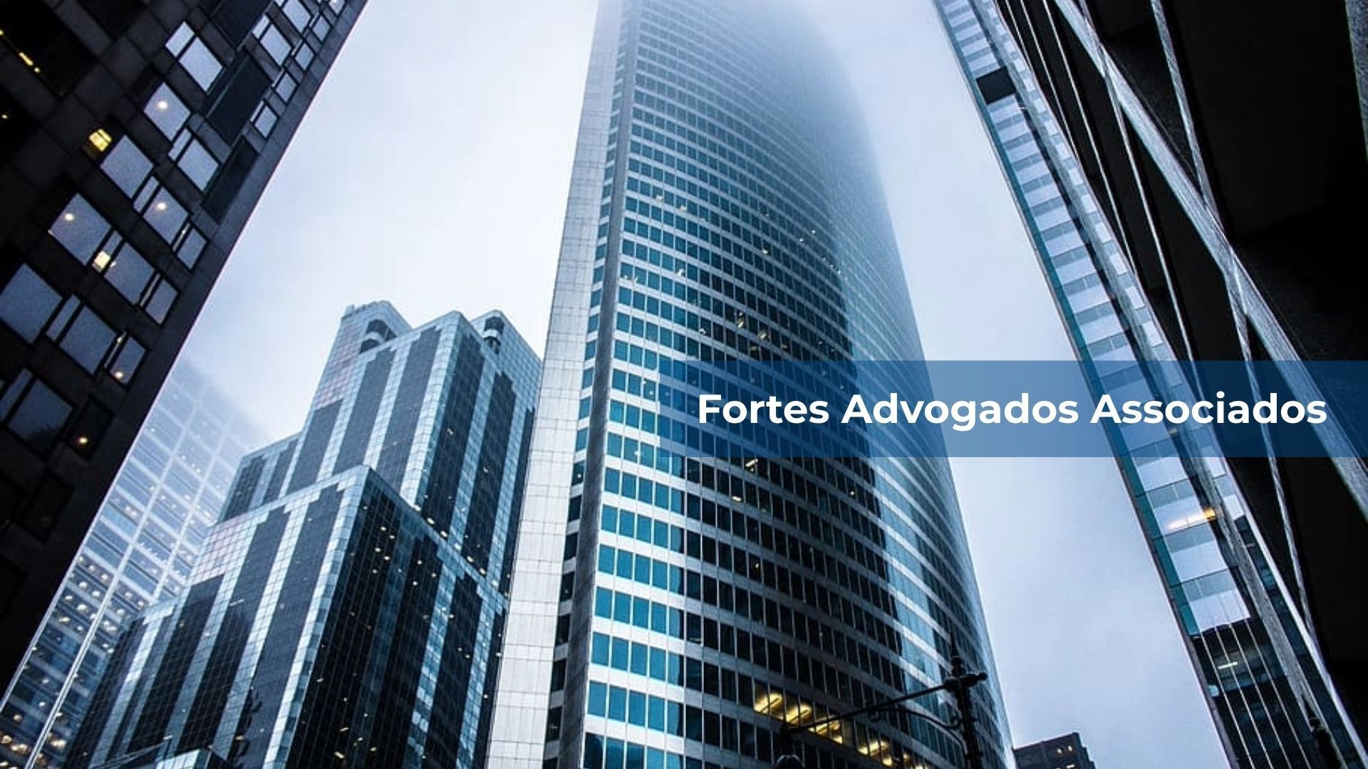 Arranha-céu alto e moderno que se ergue em direção a um céu nublado, ladeado por outros edifícios.