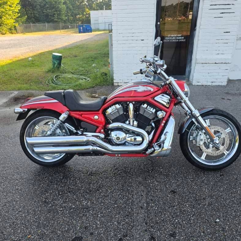 Red Harley-Davidson V-Rod motorcycle parked in front of a white building on a sunny day.