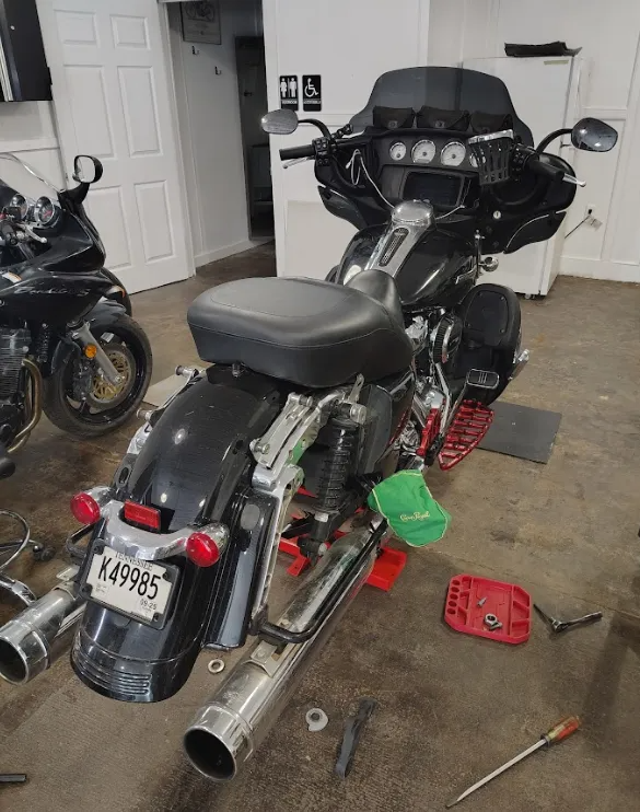 Black motorcycle in a garage. Tools and other bike in the background.